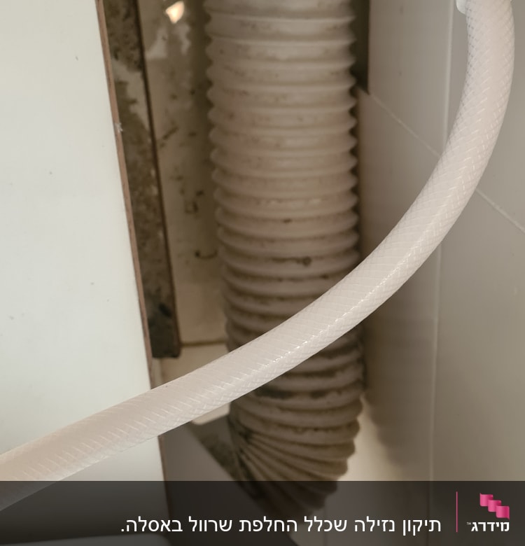 צינור מים לבן וברז מתכת ליד צינור גמיש